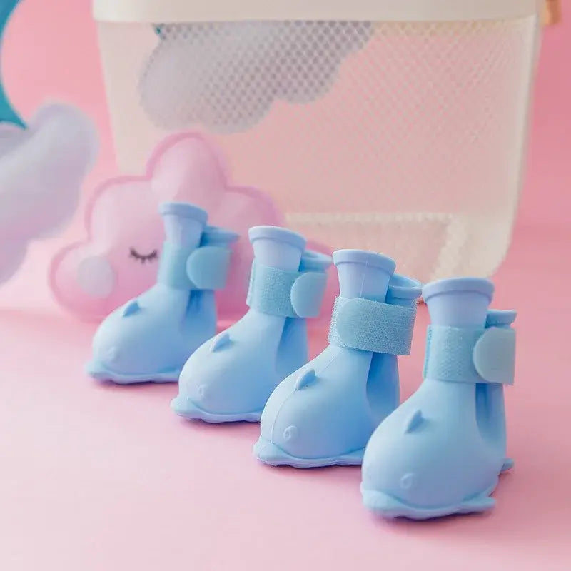 4Pcs waterproof dog boots in blue for pets, anti-slip rubber material, designed for outdoor use, on a pink background.