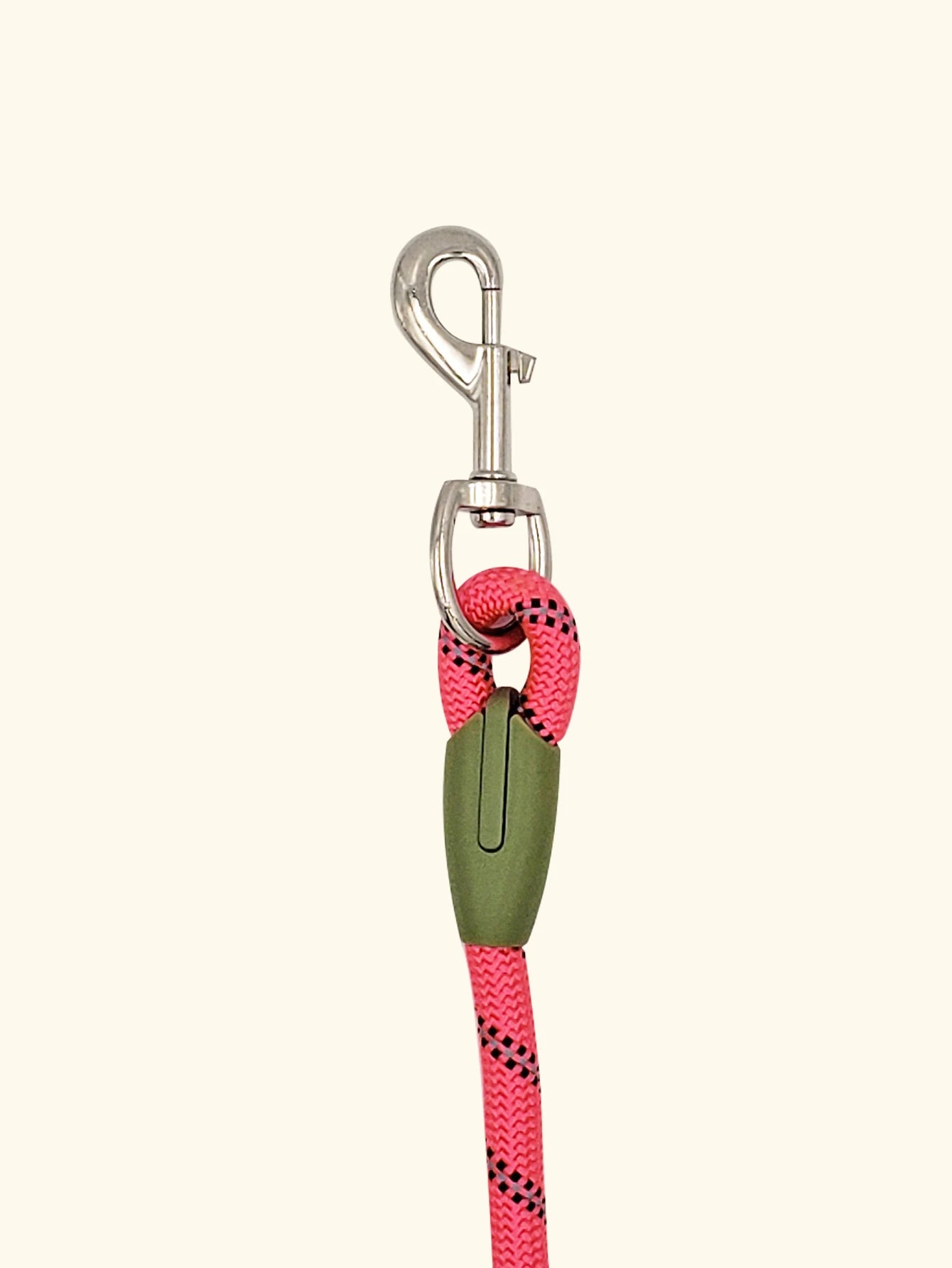 Pink rope dog leash with metal clip and green accent, isolated on beige background