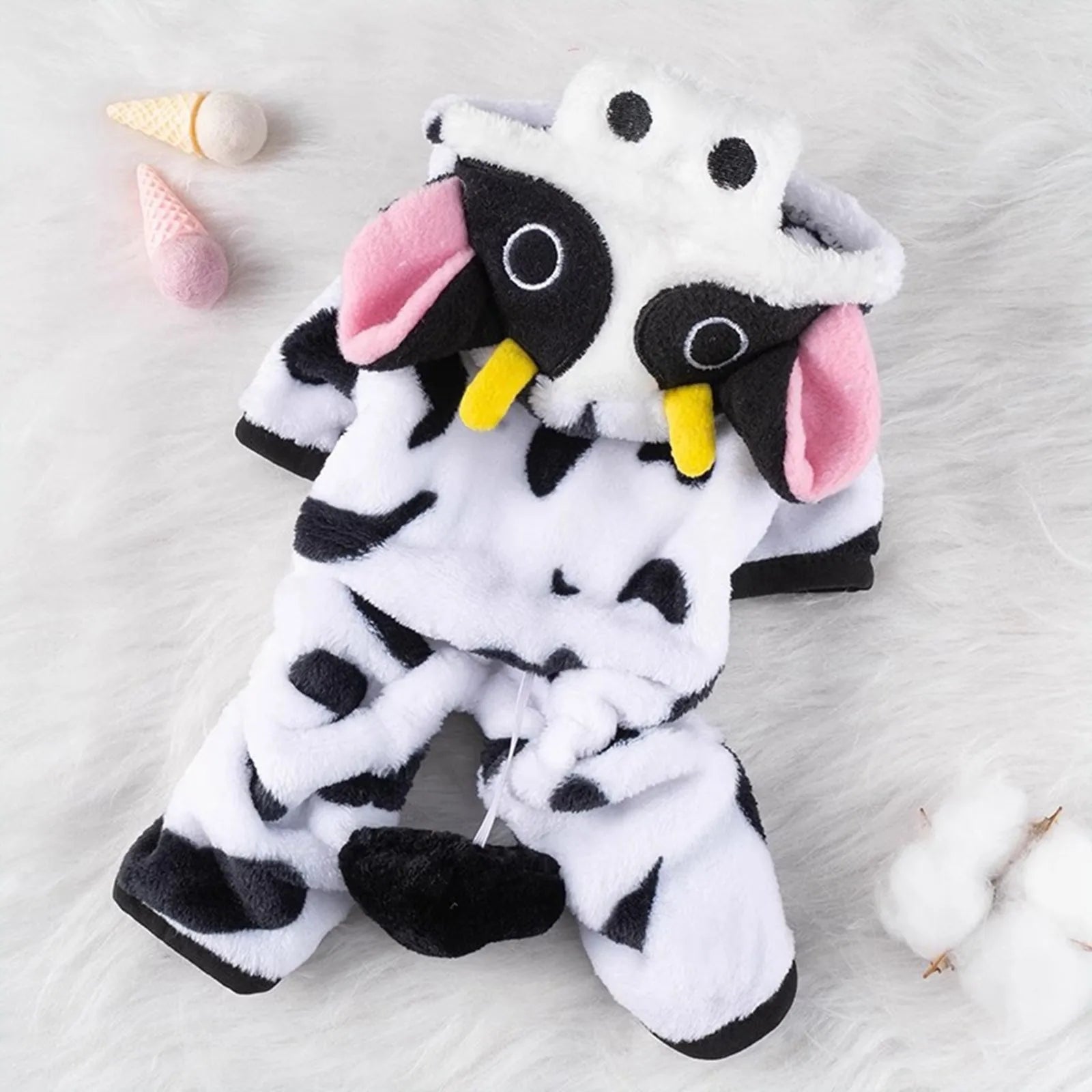 Plush dog costume resembling a cow with black spots, yellow horns, and pink ears on white fur.