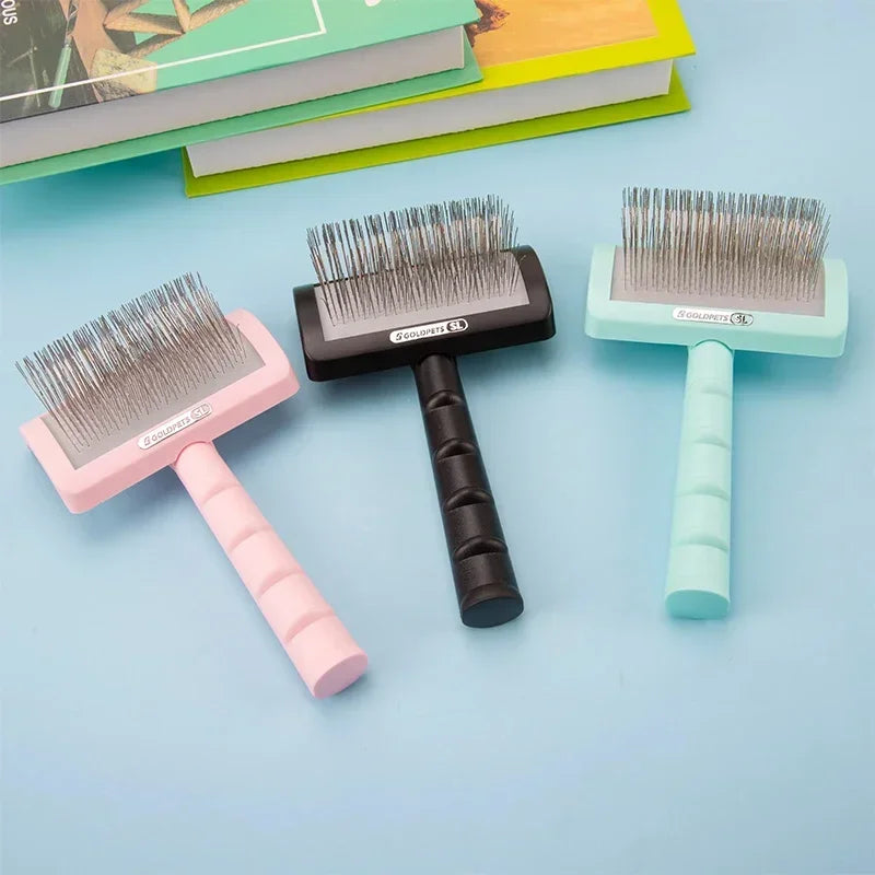 Three slicker dog grooming brushes in pink, black, and teal on a blue surface.