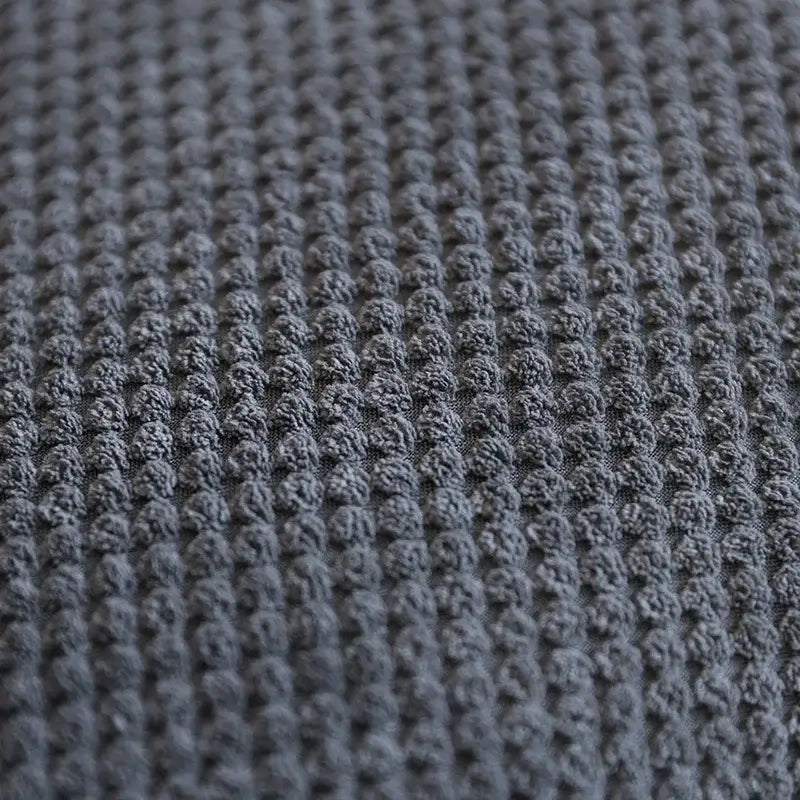 Close-up view of textured dark gray fabric pattern suitable for upholstery or bedding.