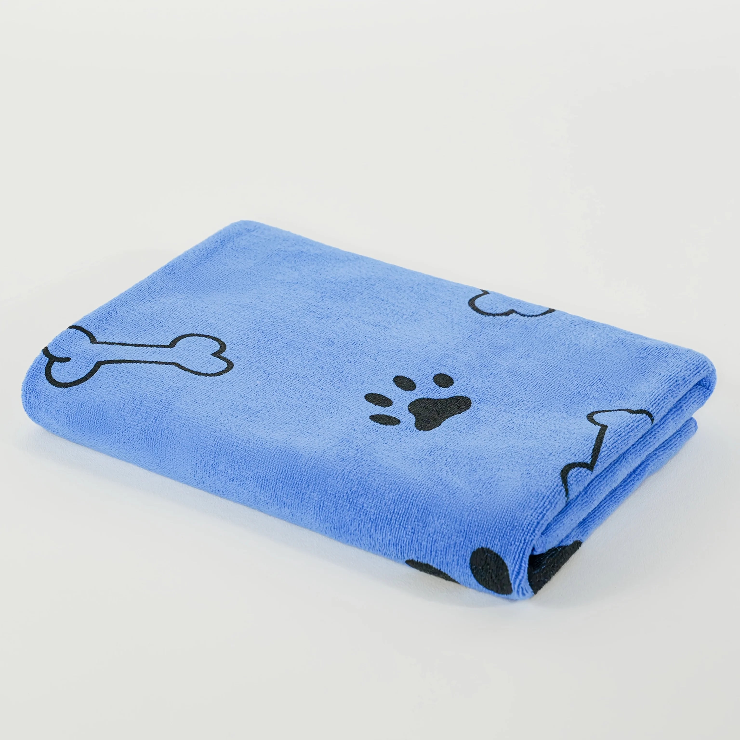 Folded blue dog towel with black bone and paw print pattern on white background