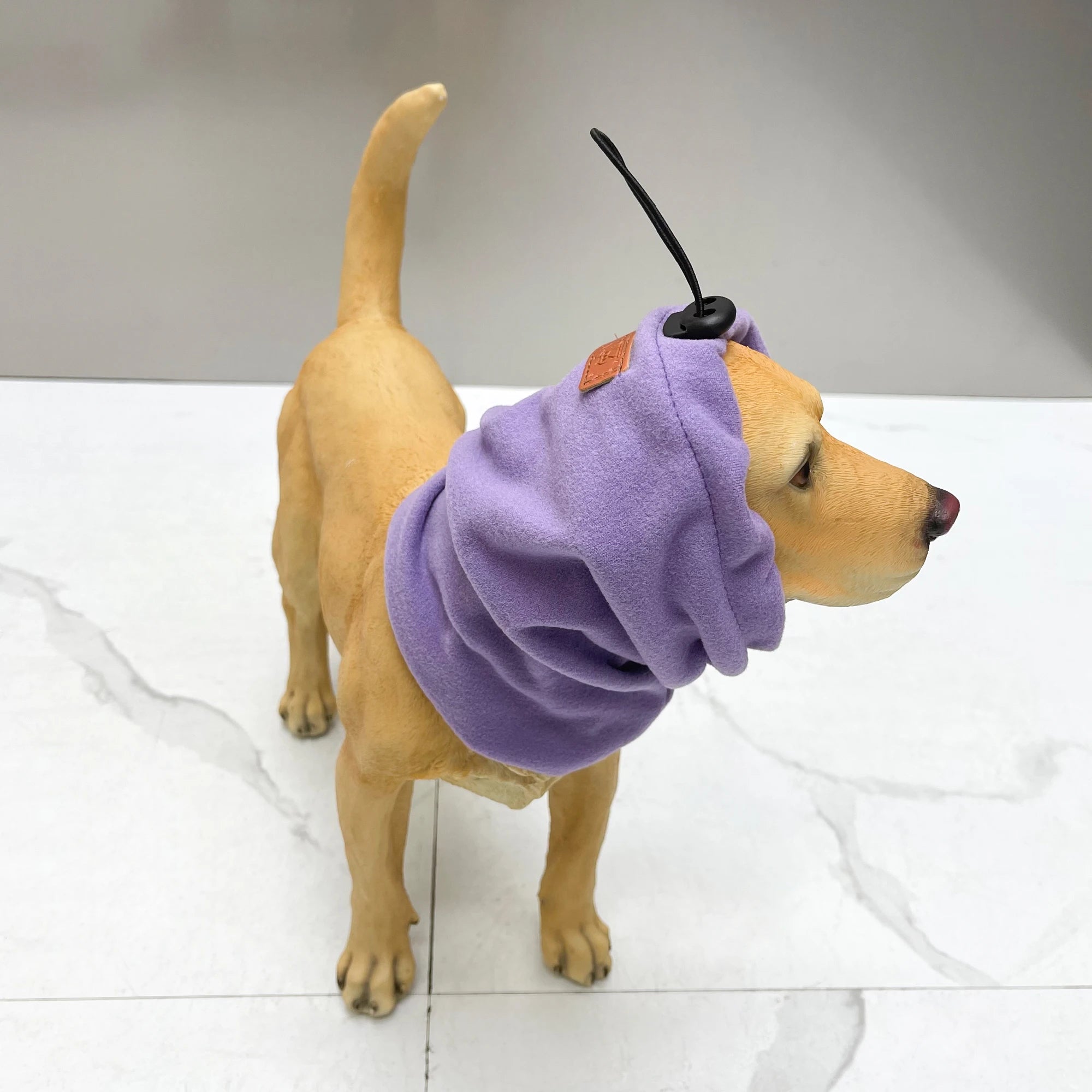 Dog wearing a purple fleece dog snood with adjustable drawstring on white floor