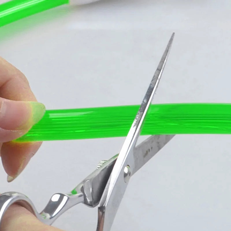 Cutting a green LED USB dog collar material with scissors for customization.