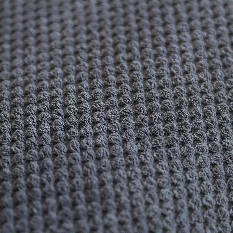Close-up of textured gray fabric surface, showcasing a woven pattern, ideal for upholstery or home decor.