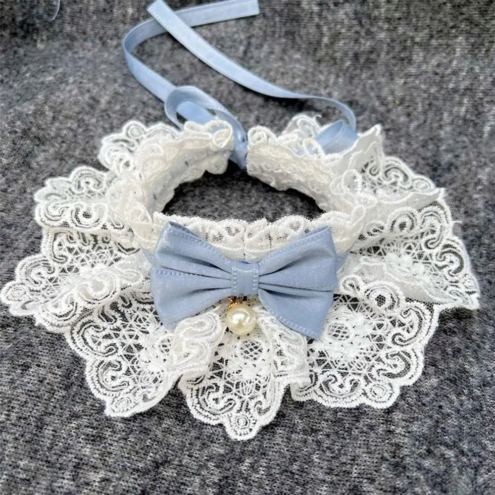 Elegant lace dog collar with blue bow and pearl charm on gray fabric background