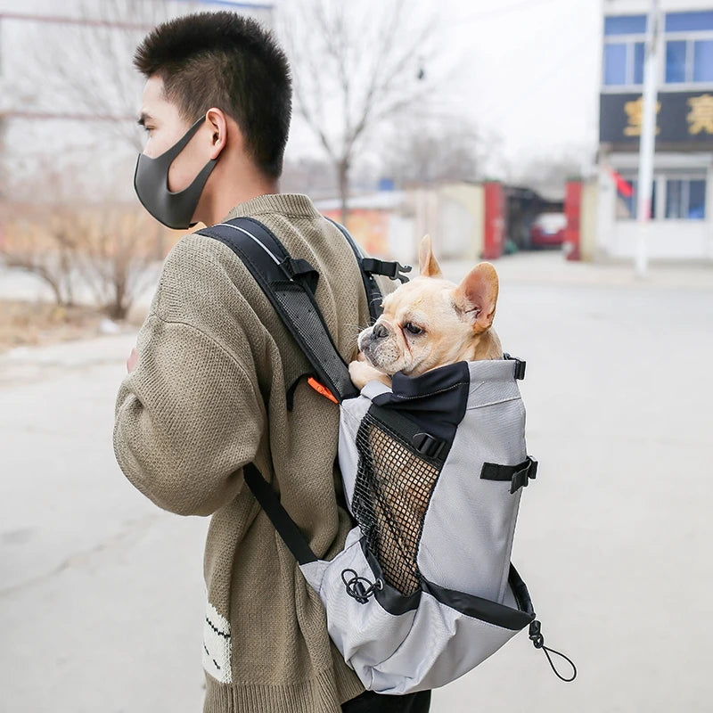 Man carrying a small dog in a breathable dog backpack carrier for outdoor travel, walking, and pet transport