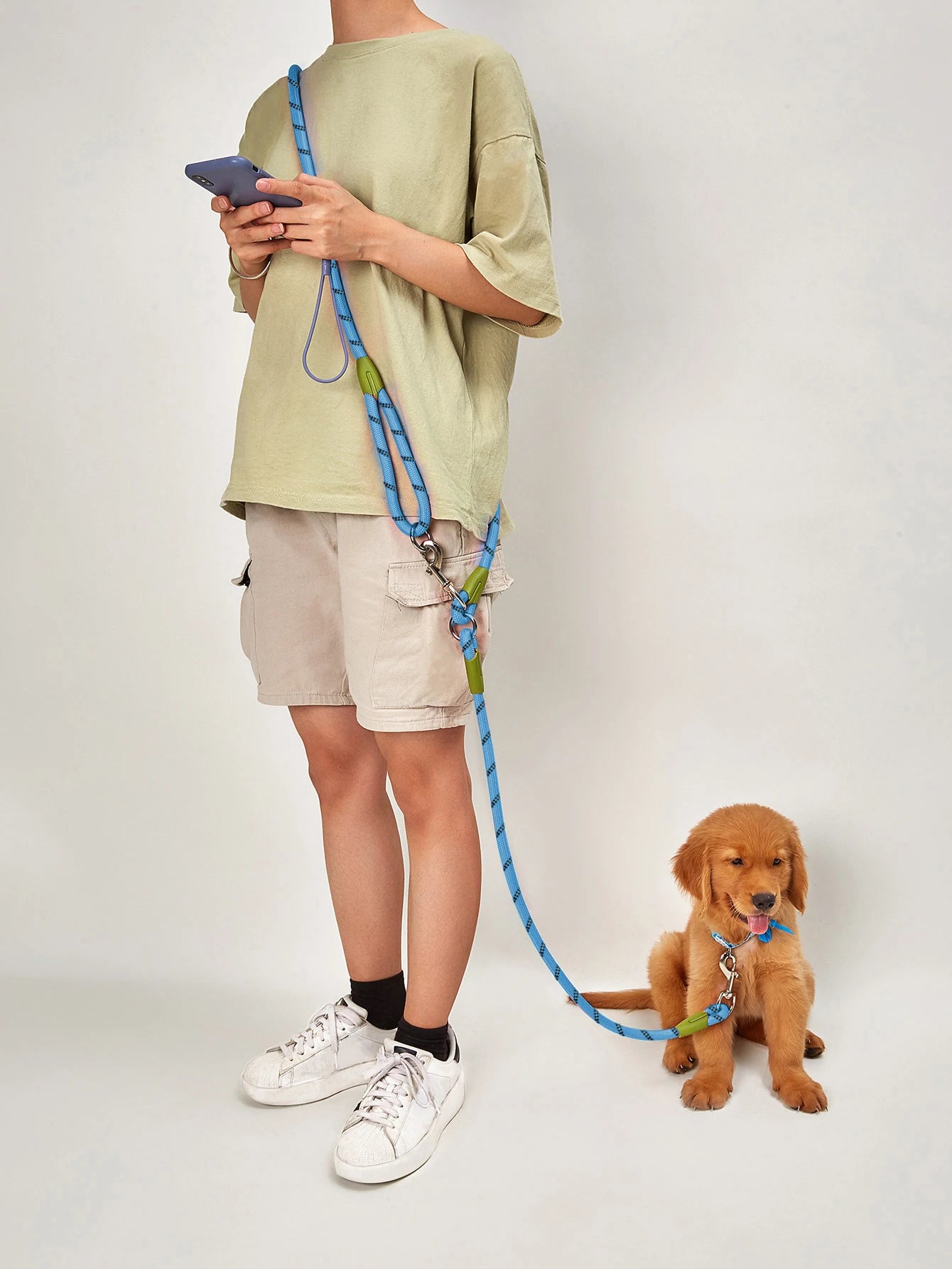 Person holding a blue dog leash, walking a golden retriever puppy indoors