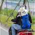 Dog in blue pet carrier backpack with helmet riding on a scooter with owner outdoors