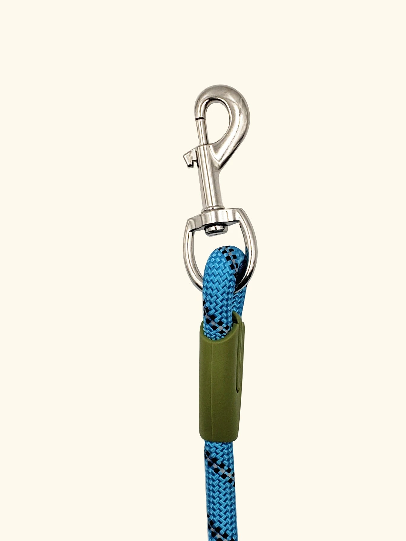 Blue braided dog leash with metal clasp and green grip on light background