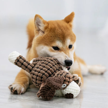 Shiba Inu puppy playing with a textured brown plush dog toy on a clean floor