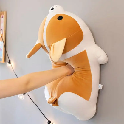 Hand squeezing a plush dog toy with brown and white fur hung on a wall, cute dog design.