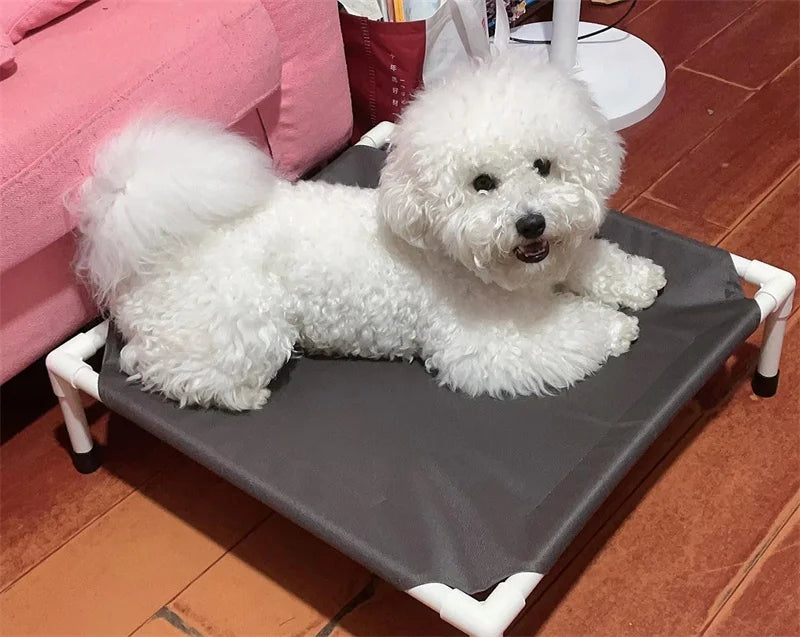 White fluffy dog resting on an elevated dog camping bed with foldable frame and washable nylon surface indoors