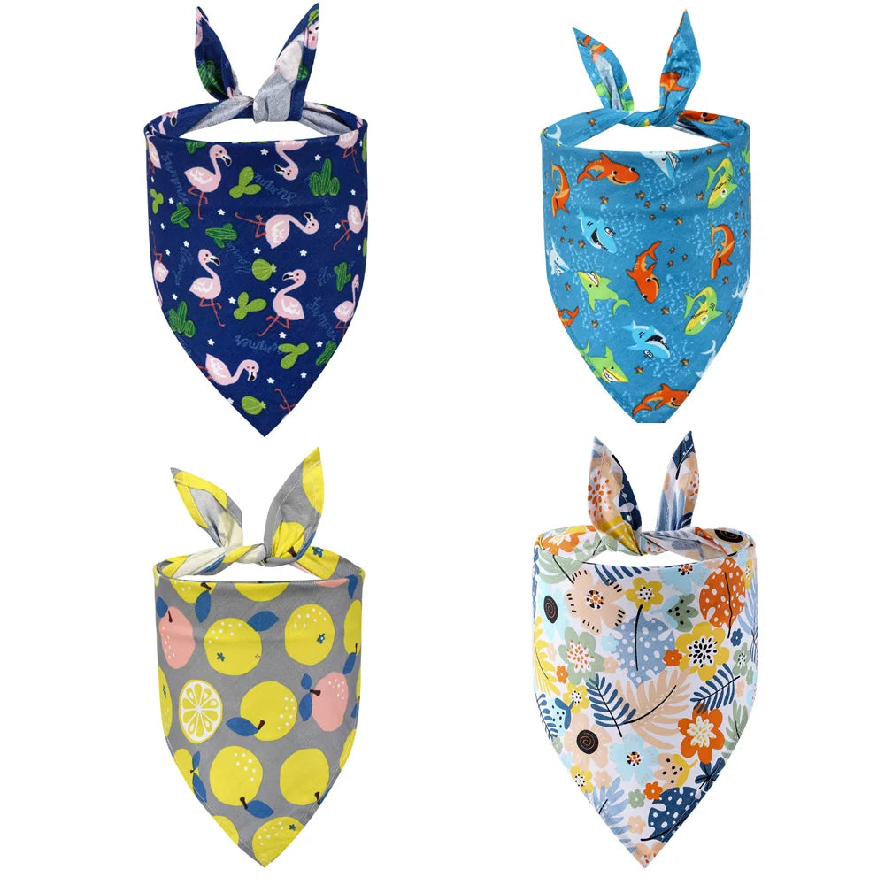 Set of four colorful dog bandanas with flamingo, shark, lemon, and floral patterns.