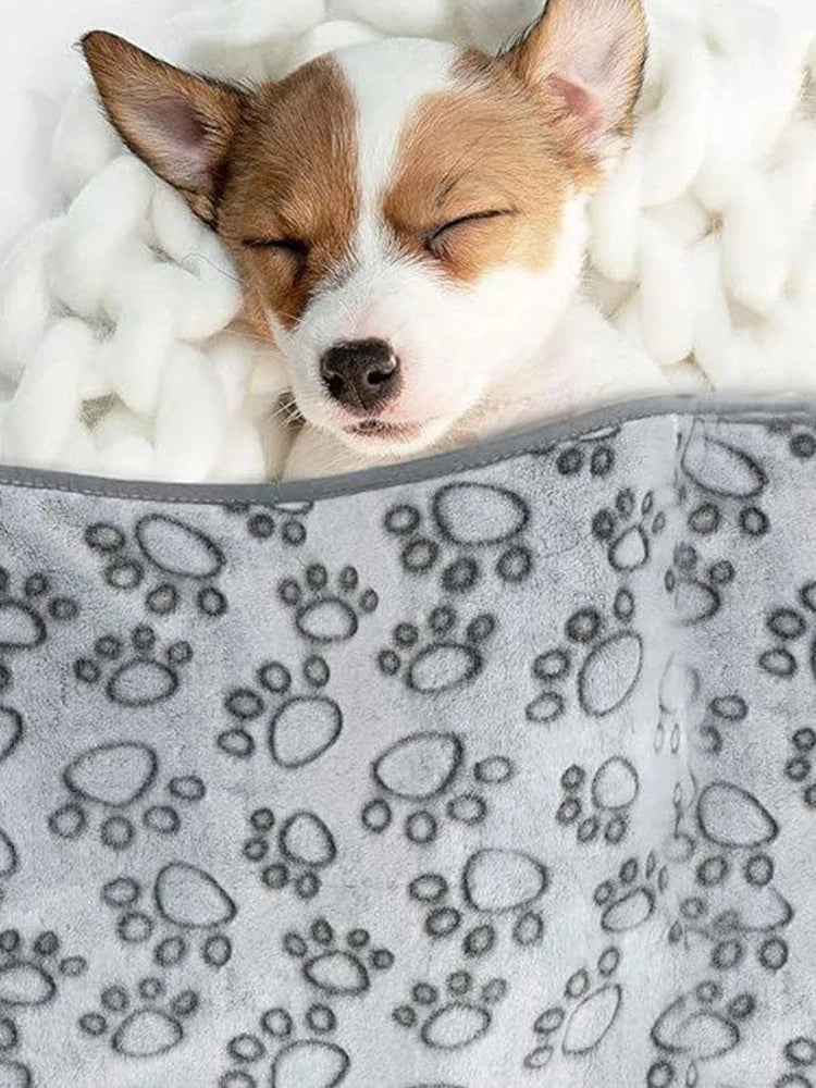 Sleepy puppy wrapped in washable soft dog blanket, gray paw print fleece pet bed for indoor comfort