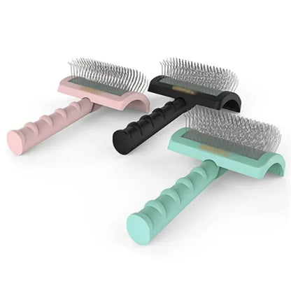 Three ergonomic dog grooming brushes with metal bristles in pink, black, and teal handles.