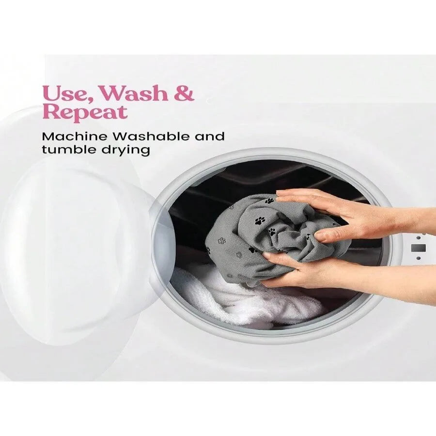 Hands placing a grey paw print dog blanket into a washing machine, machine washable pet bedding.