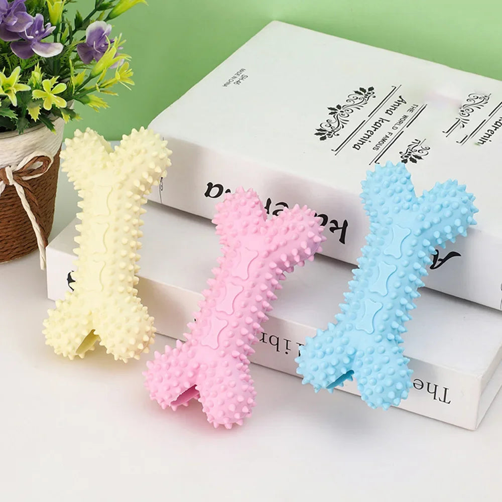 Colorful rubber bone dog toys with raised spikes for chewing, displayed on books