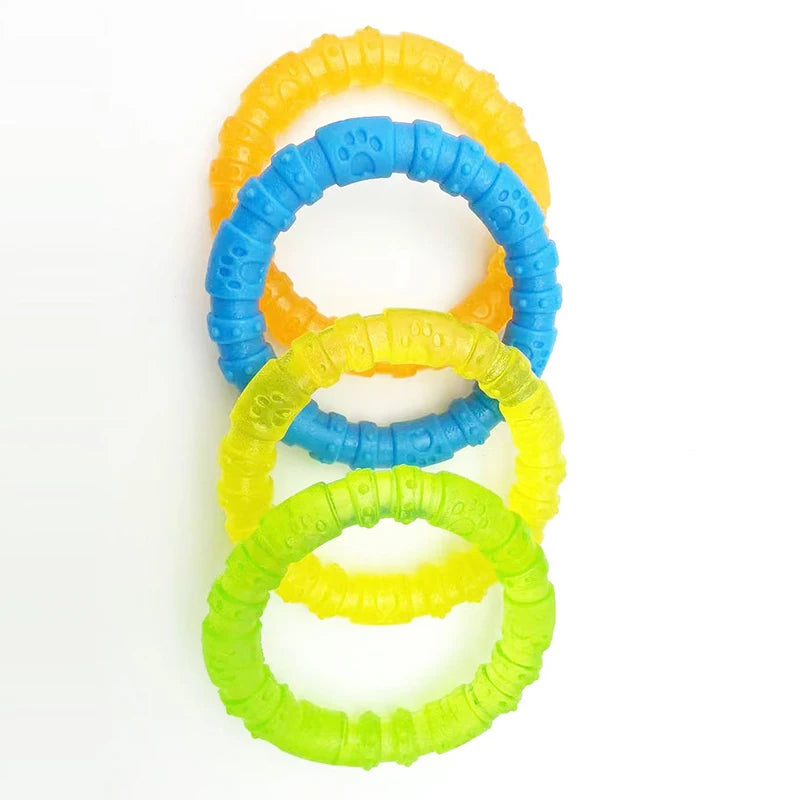 Four colorful rubber dog chew rings with paw print textures, arranged in a row on white background.