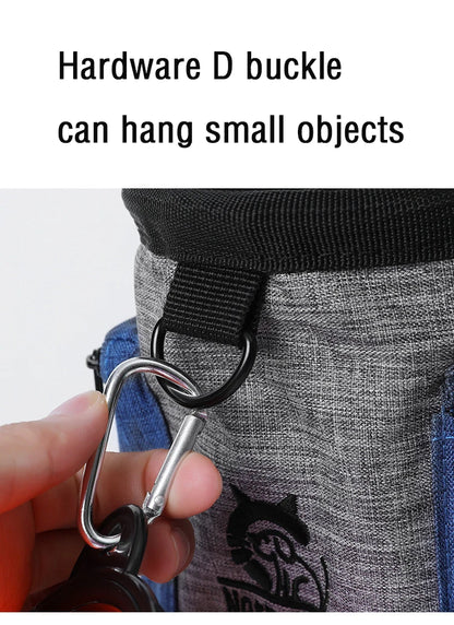 Close-up of a hardware D buckle on a gray dog accessory bag, holding a metal carabiner clip.