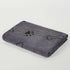 Gray dog towel with black paw print, bone, and heart patterns, folded on white background