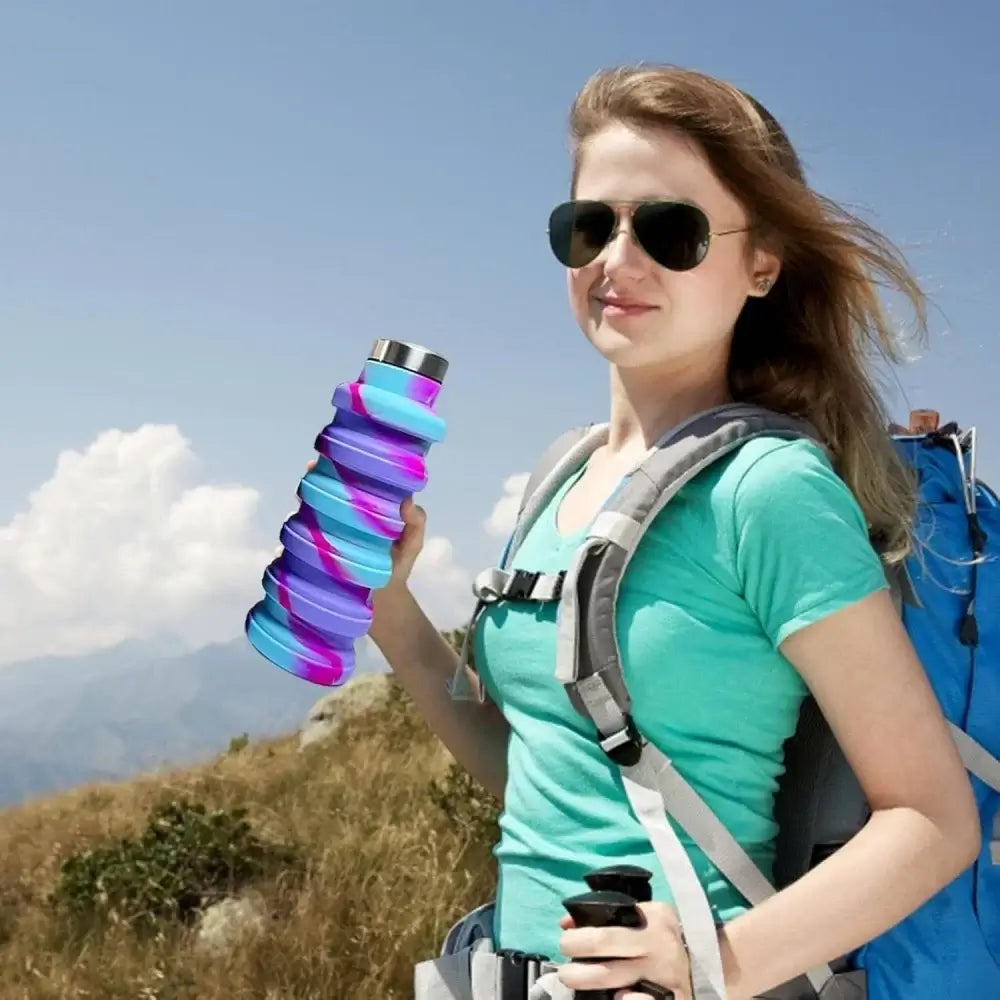 Woman hiking with a collapsible water bottle and backpack, ideal portable leak-proof hydration for travel, camping, and gym