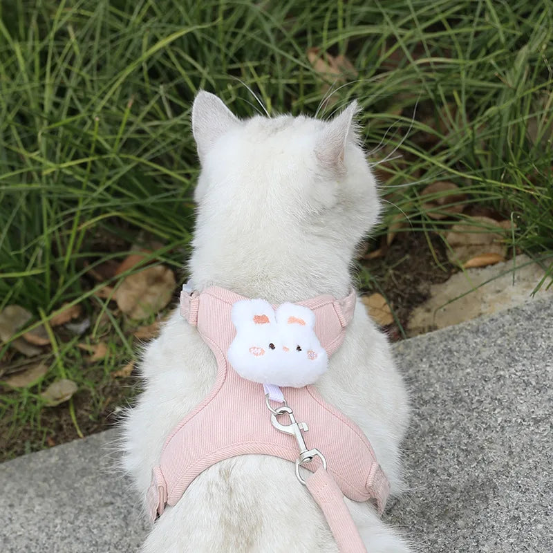 White cat wearing an adjustable cat harness leash set with pink breathable cartoon design for safe outdoor walking