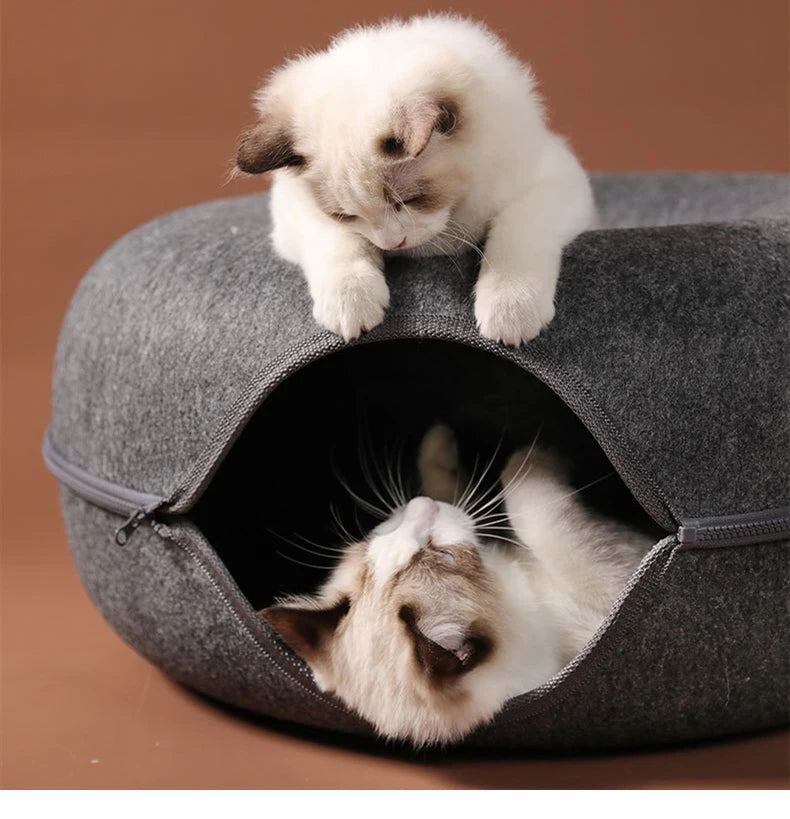 round cat tunnel bed with two cats lounging, playing, and peeking out of a cozy felt donut nest
