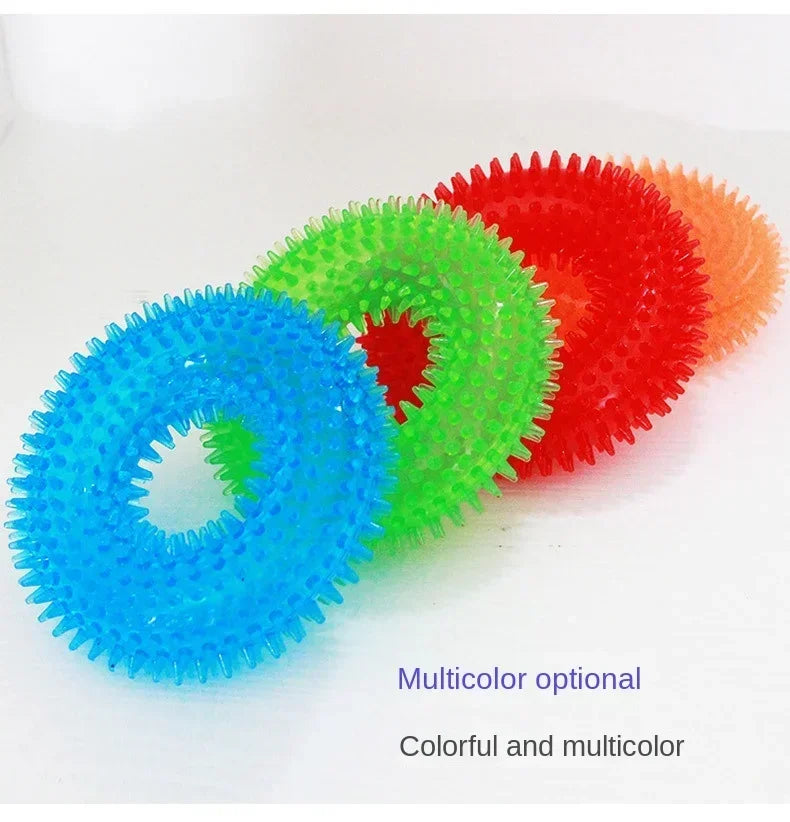Multicolor spiked rubber ring dog toys in blue, green, red, and orange on white background