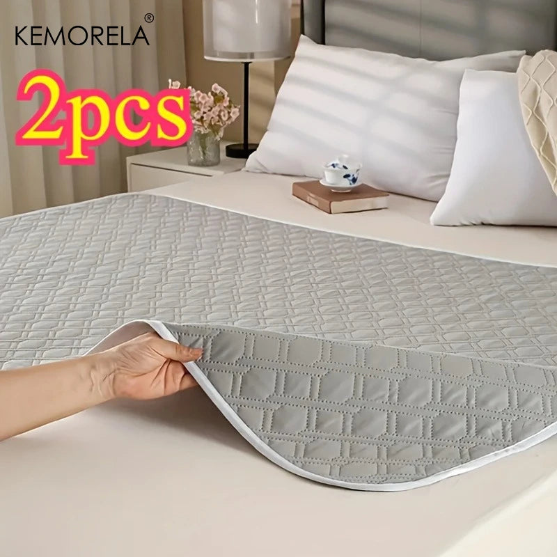 Set of two waterproof quilted bed pads for pets or incontinence, shown on a neatly made bed.