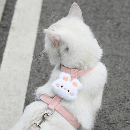 White cat wearing adjustable small dog harness leash set with pink straps and cute plush charm for safe outdoor walking