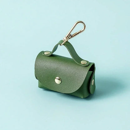 Green dog waste bag holder with metal clip on light blue background