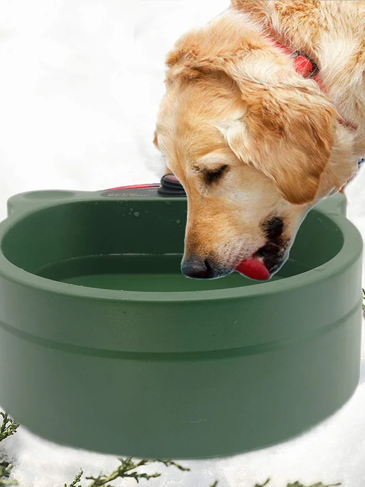 Golden retriever drinks from large green dog water bowl outdoors in winter snow