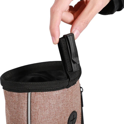 Hand holding brown dog treat pouch with black clip, ideal for pet training accessories
