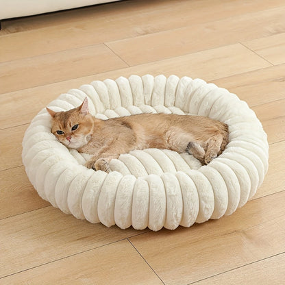 Beige plush donut cat bed with ultra soft round bolster, cozy warm nest for small medium cats and dogs on wooden floor