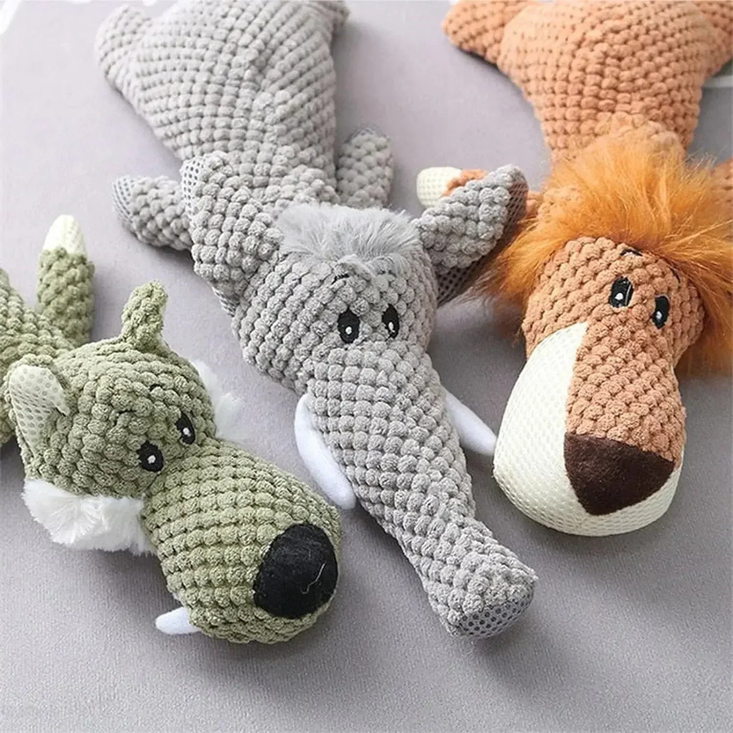 Plush dog toys shaped like a wolf, crocodile, and lion on a neutral background