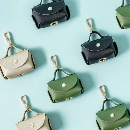 Assorted leather dog poop bag holders with gold clasps on pastel background