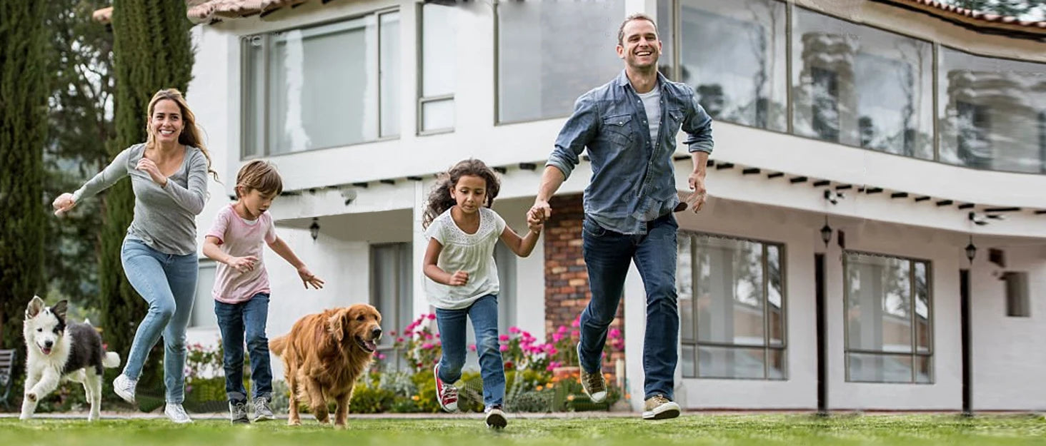 Family running with dogs in a garden, showcasing a happy moment outdoors.