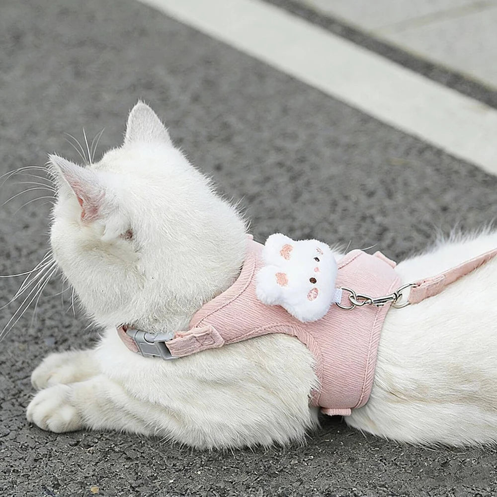 White cat wearing a pink adjustable cat harness and leash set with cute plush decoration, safe breakaway walking accessory