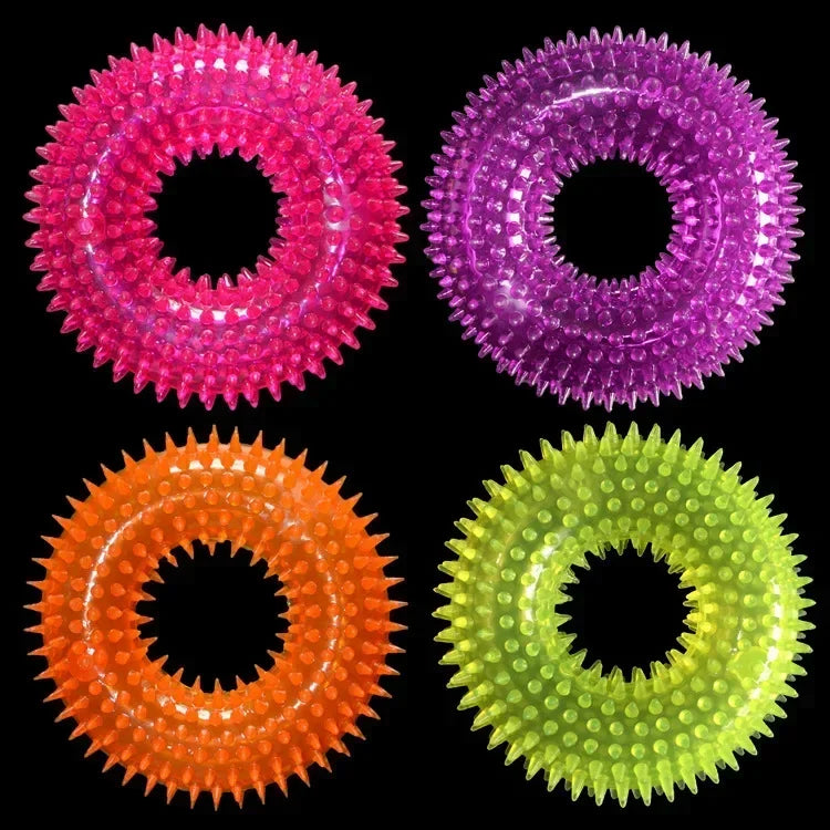 Colorful spiked rubber dog chew rings in pink, purple, orange, and green on black background