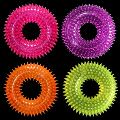 Colorful spiked rubber dog chew rings in pink, purple, orange, and green on black background