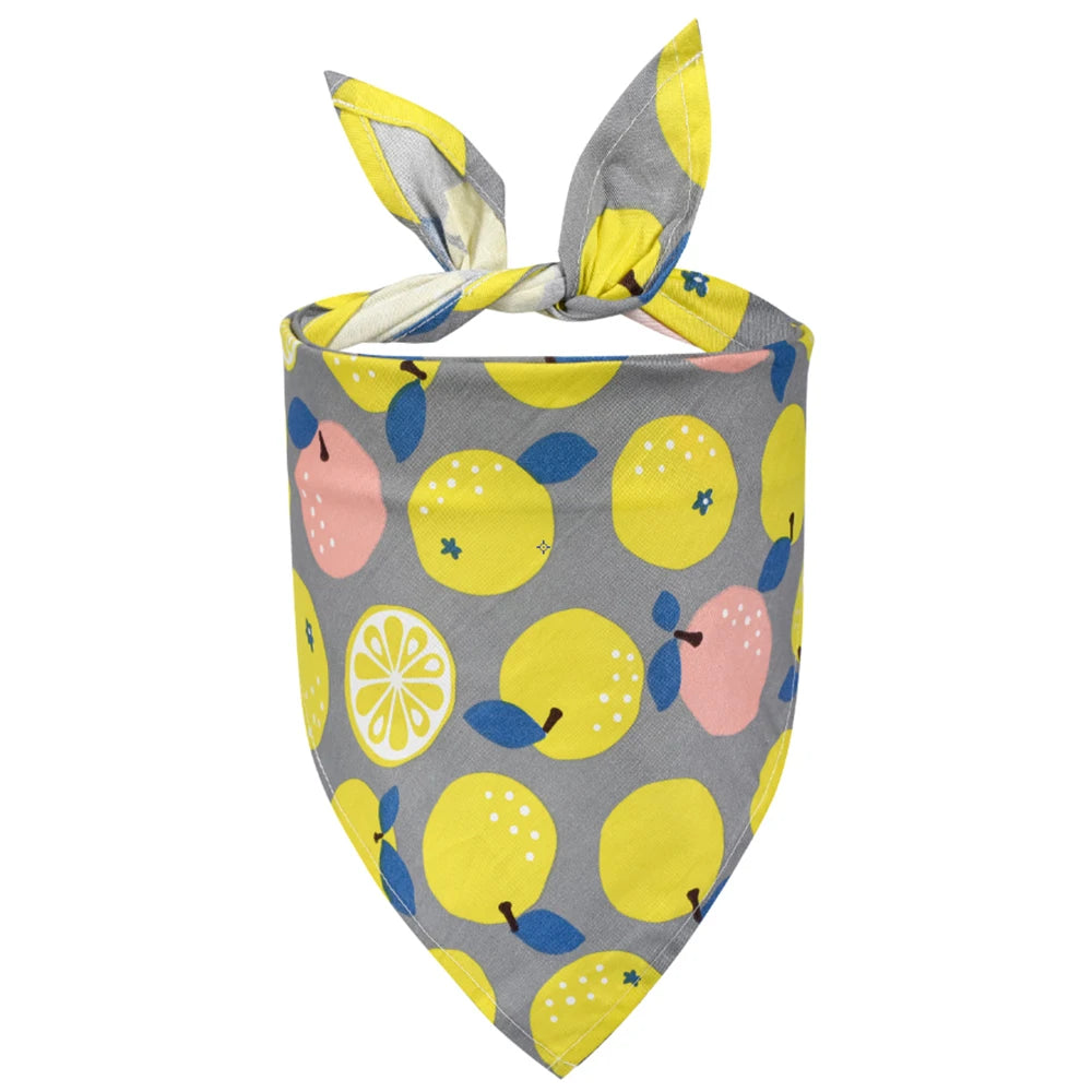 Colorful dog bandana with yellow lemon and pink fruit print on gray fabric.