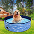 Golden retriever relaxing in a foldable dog swimming pool outdoors with blue water pattern.