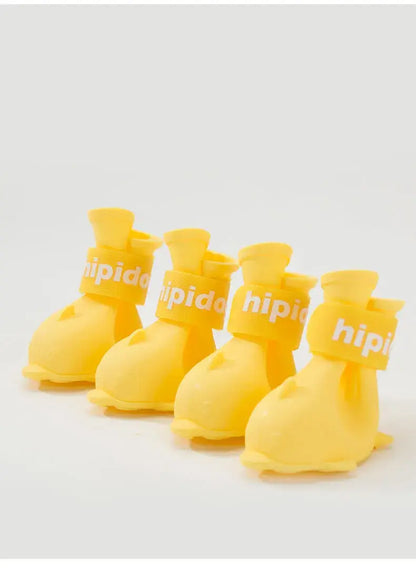 Four yellow waterproof dog boots designed for pets, featuring anti-slip rubber soles and adjustable bands.